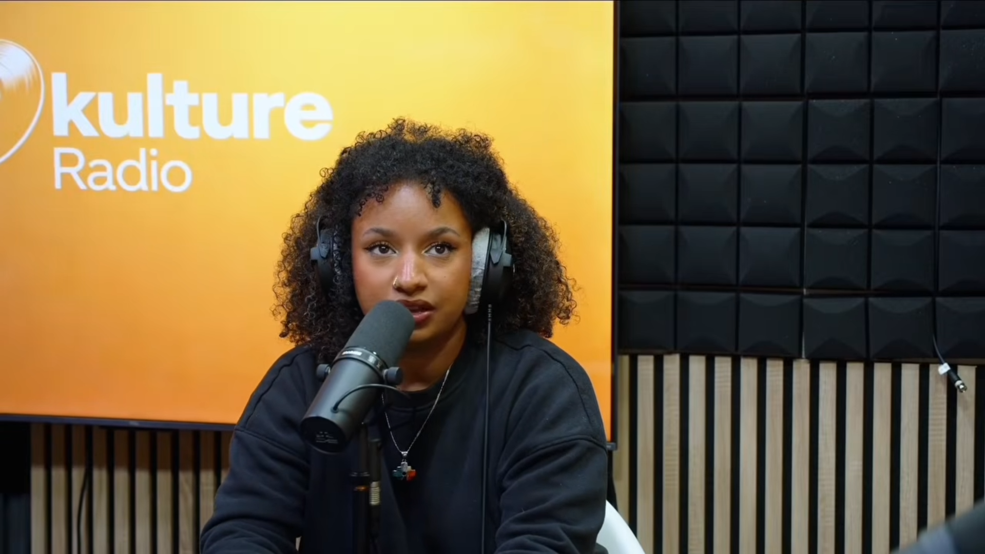 Intervenante en studio radio, micro et caméra au premier plan
