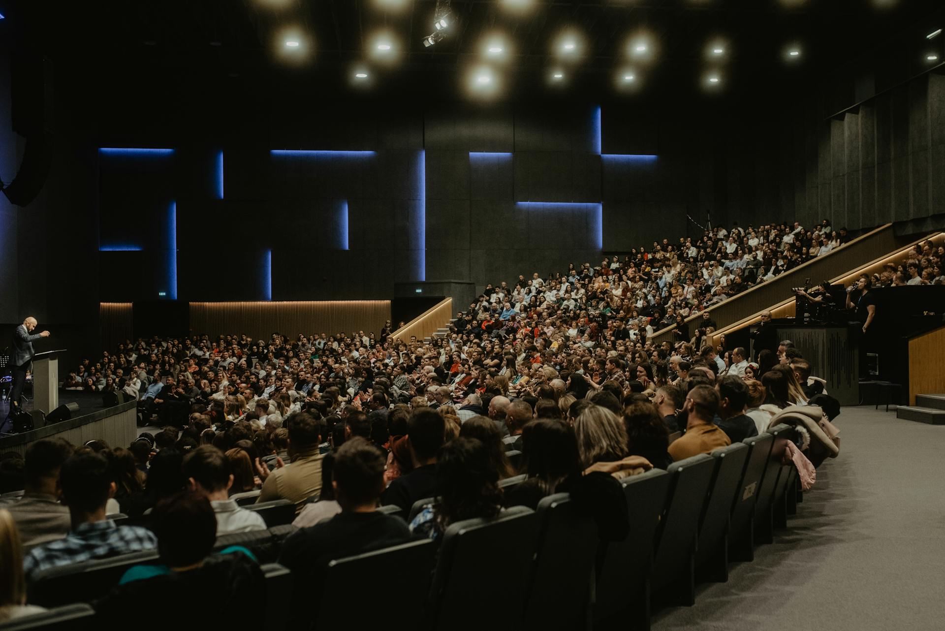Grande salle de conférence avec public nombreux et intervenant sur scène